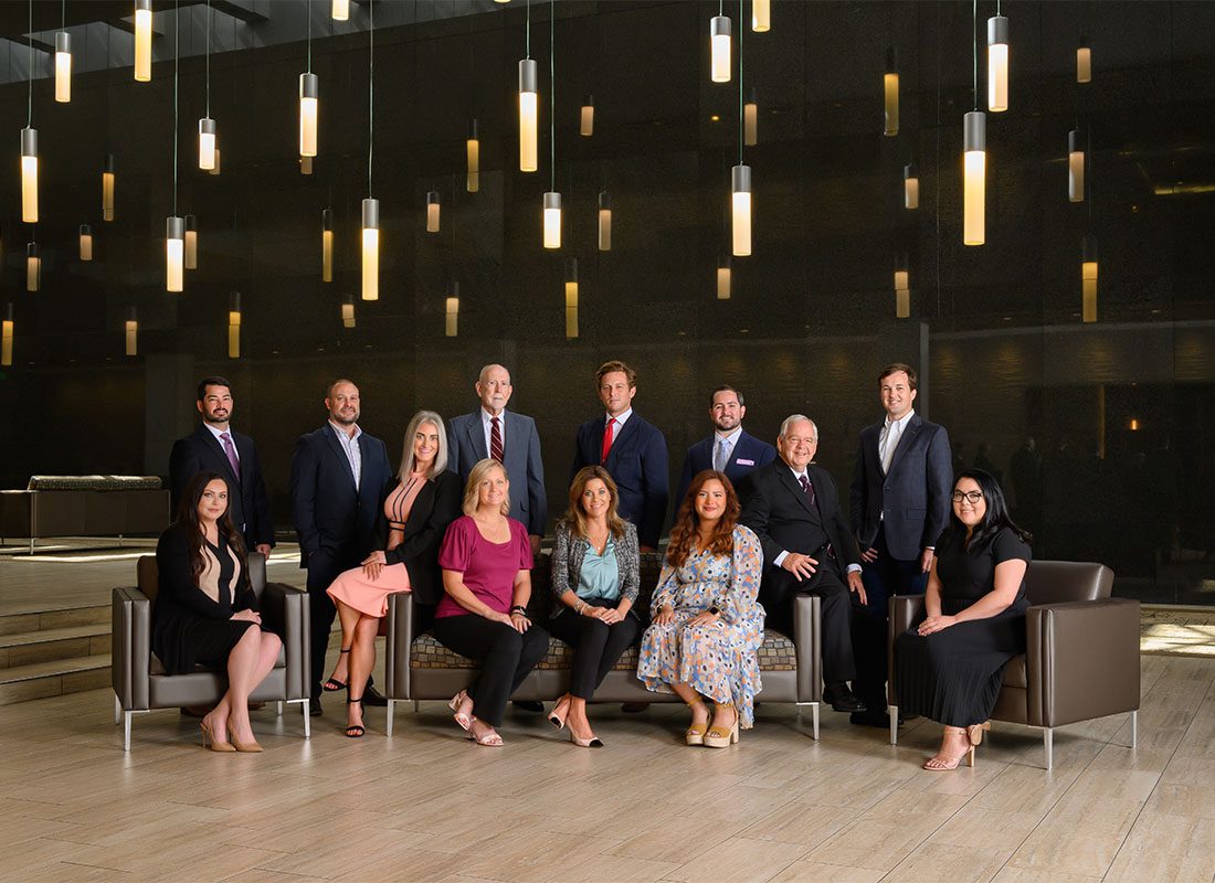 About Our Agency - Portrait of the Steward Insurance and Risk Management Team Sitting and Standing in a Modern Room with Decorative Lights Hanging From the Ceiling